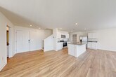 This well-designed two-story home in Rossville, GA offers a bright, contemporary interior with light-toned luxury vinyl plank flooring that flows seamlessly throughout both levels. The open-concept main floor connects the living area and kitchen in a generous, airy layout. The kitchen is a standout feature, equipped with white shaker-style cabinetry, granite countertops, stainless steel appliances including a range, microwave, and French door refrigerator, and a central island with a sink — ideal for both cooking and entertaining. A back door off the living area brings in natural light and provides outdoor access. The staircase leads to the upper level, where the bedrooms are situated. The primary suite includes a walk-in closet with wire shelving and an en-suite bathroom with a glass-enclosed shower. Additional bedrooms are well-proportioned, featuring ceiling fans and windows that invite natural light. A dedicated laundry room comes equipped with a full-size washer and dryer. Throughout the home, clean white walls, recessed lighting, and consistent flooring create a cohesive, modern aesthetic that is both functional and inviting.