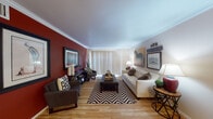 This single-floor residence offers a thoughtfully designed layout that balances style and functionality throughout. The living room serves as the centerpiece of the home, featuring warm hardwood flooring, elegant crown molding, and a striking deep red accent wall that adds dramatic character to the space. Large vertical blinds allow natural light to filter in, brightening the room and creating an inviting atmosphere. The open-concept kitchen is equipped with dark espresso cabinetry, black appliances, granite countertops, and a peninsula with bar seating — ideal for casual dining or entertaining. Crown molding continues into the kitchen and entry area, lending a cohesive, polished look. Adjacent to the living room, the dining area offers an intimate setting with continued hardwood flooring and crown molding details. The bedroom features plush carpeting, a bold red accent wall, a sliding closet with built-in shelving, and a window that welcomes natural light. The bathroom includes a granite-topped vanity with dark cabinetry, a large mirror, and access to a separate tub and shower area. Throughout the home, consistent design choices — including hardwood floors, crown molding, and coordinated accent walls — create a unified and welcoming ambiance.