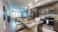 This well-appointed single-floor residence offers a thoughtfully designed open-concept layout that seamlessly connects the kitchen, dining, and living areas. The kitchen is a standout feature, showcasing rich dark-wood cabinetry, granite countertops, a white center island with bar seating, stainless steel appliances, and a classic subway tile backsplash. Globe pendant lights add a modern touch overhead. The adjacent living room is bright and welcoming, featuring large shuttered windows that invite ample natural light, wood-look flooring, a ceiling fan, and a bold teal accent wall that gives the space a vibrant, contemporary character. The two bedrooms are comfortably sized, each with wood-look flooring, generous closet space, and large windows dressed with sheer curtains for soft, diffused light. The primary bathroom features a glass-enclosed walk-in shower with large-format tile, while the secondary bathroom offers a full soaking tub and shower combination with stone-look tile surround. Both bathrooms include granite-topped vanities and wood-tone cabinetry, maintaining a cohesive aesthetic throughout. The overall ambiance is modern and inviting, with a consistent palette of warm neutrals and bold accent colors.