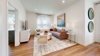 This thoughtfully designed single-floor residence offers 2 bedrooms and 2 bathrooms with a bright, modern aesthetic defined by crisp white walls, warm wood-look flooring, and recessed lighting throughout. The open-concept kitchen and living area serves as the heart of the home, featuring light wood cabinetry extending to the ceiling, a subway tile backsplash, granite countertops, stainless steel appliances, and a peninsula island with seating — ideal for both casual dining and entertaining. The adjacent living room receives generous natural light through large windows dressed with sheer curtains and blinds, creating an airy and welcoming atmosphere. The primary bedroom offers a comfortable sense of scale, a direct en-suite bathroom connection, and a walk-in closet with wire shelving systems for organized storage. The en-suite bathroom showcases a floating wood vanity with granite countertops and a large mirror with built-in lighting. A second well-sized bedroom and additional full bathroom with a tub/shower combination provide flexibility for guests or a home office. A dedicated laundry area and an impressive total of six closets round out the practical storage options. The clean, neutral design palette and consistent flooring tie the entire residence together cohesively.