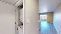 Located at 4816 McMahon Blvd NW in Albuquerque, New Mexico, this one-bedroom, one-bathroom unit offers a well-organized single-floor layout designed for comfortable everyday living. The open-concept kitchen and living room serve as the heart of the home, featuring a large peninsula with a double-basin undermount sink and light quartz-style countertops, white shaker cabinetry, stainless steel appliances including a refrigerator and gas range, and light wood-style flooring that flows throughout the entire unit. A flush ceiling light fixture brightens the kitchen space, which also includes a built-in electrical panel for added convenience. The living area extends naturally to a private balcony through sliding glass doors, bringing in natural light and outdoor views. The bedroom is a well-proportioned retreat finished with the same warm wood-style flooring, neutral wall tones, a mirrored sliding closet, and a window with blinds that allows for natural light. Built-in shelving provides additional storage options. The hallway connects all areas of the unit with ease. The bathroom is clean and functional, featuring a full tub-shower combo with white subway tile surround, brushed nickel fixtures, and wood-style flooring that ties the space together cohesively. The overall aesthetic is modern, neutral, and move-in ready.