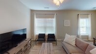 Located at 1317 Channel Marker Way in Hanahan, South Carolina, this single-floor residence offers a well-organized layout designed for comfortable everyday living. The living room is bright and welcoming, featuring large windows with blinds and sheer curtains that allow natural light to fill the space, complemented by wood-look flooring that runs throughout the home.

The kitchen is efficiently designed with rich dark wood cabinetry, granite-style countertops, a double sink, and a full suite of black appliances including a refrigerator, range, and built-in microwave. A dedicated dining area adjacent to the kitchen provides space for meals, with a window overlooking the outdoors.

The bedrooms are comfortably sized, each featuring ceiling fans with light fixtures, wood-look flooring, and windows dressed with blinds and curtain panels. The neutral wall tones create a calm, restful atmosphere throughout.

The bathrooms are finished with dark wood vanities, granite-style countertops, large mirrors with overhead lighting, and a combined tub and shower enclosure. A framed wall mirror and dresser in the hallway add to the home's cohesive, understated aesthetic. Overall, the space presents a clean, functional, and inviting environment suitable for daily living.