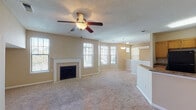 Located at 4390 Clearwater Way in Lexington, Kentucky, this two-floor home offers a well-organized layout with comfortable living spaces across both levels. The main living area is open and inviting, anchored by a classic white-mantled fireplace and bathed in natural light from multiple windows. A ceiling fan overhead and neutral-toned carpet underfoot contribute to the room's relaxed atmosphere. The living area flows naturally into the kitchen, which is separated by a breakfast bar with granite-style countertops. The kitchen features warm oak cabinetry, generous counter space, a black appliance suite including a refrigerator and range with overhead ventilation, and hardwood flooring. A pendant light above the bar area adds a subtle decorative touch. The upper level includes carpeted bedrooms, each equipped with ceiling fans and windows that bring in natural light. One bedroom features a built-in window bench, adding a charming and functional detail. A full bathroom with a tub-shower combination, white tile surround, and wood cabinetry serves the upper floor. A bright landing area at the top of the staircase with dual windows provides an airy transition between spaces. Throughout the home, warm beige tones, textured ceilings, and consistent finishes create a cohesive and comfortable living environment.