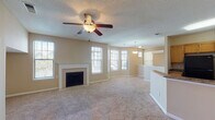 Located at 4390 Clearwater Way in Lexington, Kentucky, this two-floor home offers a well-organized layout with comfortable living spaces across both levels. The main living area is open and inviting, anchored by a classic white-mantled fireplace and bathed in natural light from multiple windows. A ceiling fan overhead and neutral-toned carpet underfoot contribute to the room's relaxed atmosphere. The living area flows naturally into the kitchen, which is separated by a breakfast bar with granite-style countertops. The kitchen features warm oak cabinetry, generous counter space, a black appliance suite including a refrigerator and range with overhead ventilation, and hardwood flooring. A pendant light above the bar area adds a subtle decorative touch. The upper level includes carpeted bedrooms, each equipped with ceiling fans and windows that bring in natural light. One bedroom features a built-in window bench, adding a charming and functional detail. A full bathroom with a tub-shower combination, white tile surround, and wood cabinetry serves the upper floor. A bright landing area at the top of the staircase with dual windows provides an airy transition between spaces. Throughout the home, warm beige tones, textured ceilings, and consistent finishes create a cohesive and comfortable living environment.