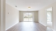 Located at 4427 Blossom St, this single-floor unit accommodates five bedrooms and one bathroom within a efficiently arranged floor plan. The living room serves as a central gathering space, featuring light wood-style flooring, neutral beige walls, and a distinctive arched sliding glass door that opens onto a balconied outdoor area with views of surrounding greenery. Natural light flows generously through the large glass door, enhancing the open, airy feel of the space.

The kitchen is outfitted with white shaker-style cabinetry, light countertops, black appliances including a range, over-the-range microwave, and dishwasher, along with a single-basin sink and track lighting overhead. Wood-style flooring continues throughout the kitchen, maintaining visual consistency with the main living area.

The bedrooms feature neutral carpet and windows overlooking outdoor green spaces, providing a calm and comfortable atmosphere. Several bedrooms include sliding glass door access or views to the balcony. The single bathroom is cleanly appointed with a white vanity, tub-shower combo with built-in shelving, and wood-style flooring, presenting a straightforward, functional design throughout the unit.