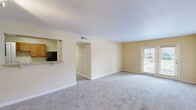 Located at 926 Cleveland St in Greenville, SC, this three-bedroom, two-bathroom unit offers a practical and comfortable single-floor layout. The open living room features neutral beige walls, plush carpeting, and a pass-through window connecting to the kitchen, creating an open, connected feel. French doors in the living area invite natural light and provide outdoor access. The galley-style kitchen is well-equipped with warm wood cabinetry, granite-look countertops, hardwood-style flooring, and black appliances including a refrigerator, range, and dishwasher, along with a dedicated pantry closet. Three carpeted bedrooms each feature large windows that bring in natural light. The spacious primary bedroom includes a full closet and direct access to an en-suite bathroom. The secondary bedrooms offer ample space and exterior views. Both bathrooms are finished with wood-toned vanity cabinetry, granite-look countertops, hardwood-style flooring, and tiled tub-shower combinations with brushed nickel fixtures. A hallway connects the bedroom wing to the main living areas, completing this well-organized and functional floor plan.