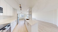 Located at 3030 Prospect St in Burlington, Ontario, this 2-bedroom, 2-bathroom unit offers a clean, modern aesthetic with thoughtful updates throughout. Light-toned hardwood flooring runs continuously across the entire space, creating a bright and cohesive feel.

The open-concept kitchen is a standout feature, showcasing sleek white high-gloss cabinetry, white quartz countertops, stainless steel appliances including a full-size refrigerator and electric range, an undermount sink with brushed gold hardware, and a white subway tile backsplash. Track lighting enhances the functional galley layout. The kitchen flows seamlessly into the living room, which features a decorative textured ceiling, a large window, and a baseboard heating unit.

The generously sized primary bedroom offers dual windows that fill the room with natural light, while the second bedroom includes mirrored sliding closet doors that amplify the sense of space. Both bathrooms are finished in crisp white, with one featuring a soaker tub and tiled shower surround, and the other offering a modern vanity with a rectangular undermount sink and frameless mirror.

The unit is situated on an upper floor, providing elevated views of the surrounding Burlington neighbourhood and lush tree canopy.