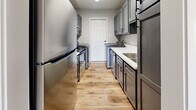 Located at 6860 Prutzman Rd in Beaumont, TX, this single-story 2-bedroom, 1-bathroom unit offers a practical and well-appointed layout. Warm-toned luxury vinyl plank flooring runs consistently throughout every room, lending a cohesive and clean aesthetic to the entire space.

The living room is bright and welcoming, featuring a front-facing window that allows natural light to fill the room, a ceiling light fixture, and direct sight lines into the kitchen. The galley-style kitchen is efficiently designed with gray shaker-style cabinetry on both sides, white countertops, stainless steel appliances including a refrigerator, range, and dishwasher, and an in-unit washer and dryer — all set beneath a textured ceiling with overhead lighting.

Both bedrooms are comfortably sized, with the primary bedroom offering generous floor space. Each bedroom features a ceiling fan with light, neutral gray walls, and windows providing natural light and outdoor views. Three closets throughout the unit provide practical storage solutions.

The bathroom includes a gray vanity with storage drawers, a white countertop, a full tub-shower combination with white surround tile, and a medicine cabinet above. Textured ceilings are present throughout the unit, and clean white baseboards frame every room, contributing to a fresh, move-in-ready appearance.