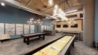 This single-floor entertainment lounge offers a well-appointed games and social space with a distinctive industrial-modern aesthetic. The exposed ceiling reveals raw ductwork and structural elements, adding an urban, loft-like character to the environment. A series of large globe pendant lights cascades dramatically across the space, complemented by sculptural branching chandeliers that cast a warm, ambient glow throughout.

The games area is a central highlight, featuring a full-size billiards table and a regulation-length shuffleboard table, both positioned for comfortable play. Multiple flat-screen televisions are mounted across the walls, making the space well-suited for watching broadcasts or hosting group events. Patterned carpet flooring anchors the layout while adding texture underfoot.

The walls are treated with a combination of teal-painted surfaces and decorative paneling featuring abstract line work, contributing to a curated, contemporary look. Frosted glass partitions and high bar-height tables with stools provide additional seating and subtle zoning within the open floor plan. The overall ambiance is energetic yet refined, balancing functionality with thoughtful design details throughout.