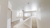 This single-floor residence offers a clean, contemporary design with a neutral color palette and an abundance of natural light throughout. The open living and dining area is anchored by light wood-style flooring, a ceiling fan with light fixture, and multiple windows fitted with horizontal blinds that allow natural light to fill the space. A pass-through counter connects the living area to the kitchen, enhancing the open feel. The kitchen is well-equipped with white cabinetry, quartz-style countertops, a classic white subway tile backsplash, and a full suite of stainless steel appliances including a gas range, over-the-range microwave, refrigerator, and dishwasher. Wood-style flooring continues through the kitchen, which provides ample counter and storage space in a well-organized galley-style layout. The bedroom features plush carpeting, a ceiling fan, and a generous closet, providing a comfortable and quiet retreat. The full bathroom is outfitted with a wide vanity featuring a quartz countertop and undermount sink, a large mirror, and a tub-shower combination with tile surround. Wood-style flooring ties the bathroom together with the rest of the home. Overall, the space presents a fresh, move-in-ready environment with consistent finishes and a light, airy ambiance.