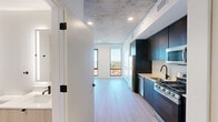Located at 625 North 2nd Avenue in the heart of Phoenix, AZ, this efficiently designed studio presents a thoughtfully arranged single-floor layout that maximizes every square foot. The space makes a strong architectural statement with its exposed concrete ceiling, which lends an industrial-modern character throughout the open living, dining, and kitchen area. Light hardwood flooring runs continuously underfoot, creating a warm contrast against the raw ceiling above.

The kitchen is a standout feature, outfitted with floor-to-ceiling dark cabinetry, light quartz countertops, a white tile backsplash, and a full suite of stainless steel appliances including a gas range, built-in microwave, dishwasher, and a matte black pull-down faucet at the sink. The open layout connects the kitchen seamlessly to the living and dining area.

Tall, narrow floor-to-ceiling windows at the far end of the living space flood the room with natural light and frame elevated views of the Phoenix skyline and surrounding cityscape. The bathroom features large-format tile flooring, a floating wood vanity, an integrated sink with a contemporary faucet, and a backlit mirror. Additional amenities include a dedicated closet, laundry, and a distinctive teal entry door that adds a bold design accent at the entrance.