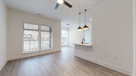 This thoughtfully designed 1-bedroom, 1-bathroom residence offers a clean, contemporary aesthetic across a single floor. Light gray wood-style flooring runs continuously throughout, complementing the bright white walls and creating a cohesive, modern feel.

The open-concept living and kitchen area forms the heart of the home. The kitchen is outfitted with dark, textured cabinetry, white countertops, and a full suite of stainless steel appliances, including a refrigerator, range, microwave, and dishwasher. A peninsula with pendant lighting in a brushed gold finish provides a natural divide between the kitchen and the living area, which features a ceiling fan and large windows that invite generous natural light and outdoor views.

The bedroom is a well-proportioned retreat with a ceiling fan, large windows offering exterior views, and access to a dedicated closet. The bathroom continues the space's clean design language, featuring a soaking tub with matte black fixtures and subway tile surround, paired with elegant gray panel doors and matching hardware.

Multiple oversized windows fitted with horizontal blinds are found throughout, ensuring each room benefits from natural light. The overall ambiance is bright, airy, and move-in ready, with modern finishes that strike a balance between style and functionality.