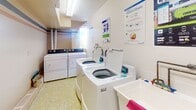 Located at 262 Rose St in Barrie, Ontario, this shared laundry facility is a well-organized, single-floor utility space designed for communal use. The room is efficiently laid out to accommodate multiple top-loading washing machines and front-loading dryers, providing ample capacity for residents. A utility sink is also present, offering added convenience for hand-washing or pre-treating garments.

The space features distinctive yellow-green mosaic tile flooring throughout, which adds a subtle visual character to the otherwise clean and functional interior. The walls are finished in a soft, neutral tone, contributing to a bright and tidy atmosphere. Ventilation is addressed through wall-mounted HVAC grilles, and an electrical panel is accessible along one wall.

Natural light enters through a window, supplemented by overhead fluorescent lighting to ensure the space remains well-lit at all times. Instructional signage for proper washer and dryer usage is posted on the walls, making the facility straightforward to navigate. Floor drains are integrated into the tile layout, reflecting a practical approach to maintenance and cleanliness. The overall design prioritizes functionality and ease of use, making this a reliable shared amenity.