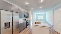 Located at 500 River Knoll Way in Columbus, Georgia, this single-story residence offers a well-designed layout across a comfortable footprint, accommodating two bedrooms and two full bathrooms. The open-concept kitchen and living area serves as the heart of the home, showcasing a central island with a granite countertop and undermount sink, sleek gray cabinetry, a white subway tile backsplash, and a full suite of stainless steel appliances including a refrigerator, range, and built-in microwave. Light wood-look flooring runs throughout, complementing the neutral color palette and recessed lighting that keeps the space bright and inviting.

The bedrooms are well-proportioned, each featuring large windows that invite natural light and outdoor views of the surrounding landscape. One bedroom includes a ceiling fan for added comfort. Both bedrooms are supported by dedicated closets with wire shelving systems for organized storage. The bathrooms mirror the kitchen's modern aesthetic, with granite-topped gray vanities and tiled tub-shower combinations. A dedicated laundry area houses a full-size washer and dryer, adding everyday convenience to this thoughtfully arranged single-floor home.