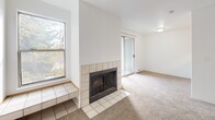 Located in Bothell, WA, this one-bedroom, two-bathroom residence offers a well-organized single-floor layout designed for comfortable everyday living. The combined living and dining area is a bright, carpeted space anchored by a tile-surround wood-burning fireplace with a built-in tile hearth bench and a sliding glass door that opens to a private balcony, allowing natural light and outdoor views to flow in. Adjacent to the living area, the kitchen features warm honey-toned wood cabinetry, white appliances including a dishwasher, electric range, and refrigerator, white countertops, and light hardwood-style flooring. A pass-through opening connects the kitchen to the dining area, enhancing the open feel of the space. The bedroom is a generously sized, carpeted retreat with a large double-door closet and a window overlooking the greenery outside. Two bathrooms provide added convenience, with one showcasing a warm wood vanity, white countertop, and a large mirror with overhead lighting. A hallway with an additional closet offers plentiful storage, while a dedicated laundry area adds everyday practicality. Throughout the residence, oak-toned doors and trim provide a consistent, cohesive design aesthetic.
