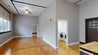 Located at 751 2nd Ave S in Clinton, Iowa, this two-bedroom, one-bathroom single-floor residence offers a well-designed layout with a clean, modern aesthetic. Throughout the unit, warm-toned hardwood floors provide a cohesive foundation, complemented by neutral gray walls and crisp white trim.

The open-concept kitchen and living area serves as the heart of the home. The kitchen is equipped with dark-stained cabinetry, granite countertops, full black appliance suite including refrigerator, range, microwave, and dishwasher, and a freestanding island with a butcher block top for added prep and storage space. Soaring ceilings and a ceiling fan enhance the airy feel of this central area.

The spacious living room benefits from large windows fitted with blinds, allowing ample natural light and views of the surrounding greenery. Both bedrooms are well-proportioned, each featuring hardwood floors, ceiling fans, and large windows. The primary bedroom is generously sized and includes access to a dedicated closet. A second closet serves additional storage needs.

The bathroom offers a granite-topped vanity with an open under-sink design, mirror, and wall lighting. A dedicated utility room houses a full-size washer and dryer, providing convenient in-unit laundry. The overall space presents a bright, functional, and comfortable living environment.
