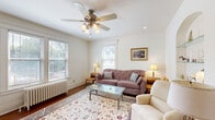 Located on W Ferry St in Buffalo's historic West Side, this well-appointed 1-bedroom, 1-bathroom unit showcases classic architectural character throughout its thoughtfully organized single-floor layout. An elegant arched entryway connects the hallway to the bright living room, which features rich hardwood floors, a ceiling fan with light fixture, large windows admitting generous natural light, a cast-iron radiator, and a charming built-in arched wall niche with glass shelving. The adjacent dining area offers an intimate setting with wainscoting detail. The kitchen is equipped with warm wood cabinetry, ample counter space, a gas range, dishwasher, refrigerator, and multiple windows that flood the space with daylight. The bedroom is a comfortable retreat with a ceiling fan, natural light from large windows, a cast-iron radiator, and hardwood floors. The full bathroom retains its classic character with white penny-tile flooring, navy blue tile accents, a pedestal-style vanity, a soaking tub, and a radiator. Throughout the unit, cream-toned walls, consistent hardwood flooring, and period architectural details create a cohesive, warm, and inviting ambiance.