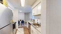 This thoughtfully designed one-bedroom, one-bathroom residence offers a functional and stylish layout across a single floor. The galley-style kitchen is a standout feature, showcasing white shaker cabinetry, granite-look countertops, a classic subway tile backsplash, and a full suite of stainless steel appliances including a refrigerator, electric range with overhead microwave, and dishwasher. Hardwood-style flooring runs throughout the unit, adding warmth and continuity to the space.

The combined living and dining area is bright and inviting, with large sliding glass doors that flood the room with natural light and provide outdoor views. A ceiling fan adds comfort to the living space, which also features a marble-surround fireplace as a focal point. The dining area comfortably accommodates a four-seat table and is accented by framed wall art.

The spacious primary bedroom offers generous proportions, large windows with outdoor views, and ample room for a full bedroom suite. The bathroom is clean and well-finished, featuring a granite-topped vanity with white cabinetry, a framed mirror, and a full tub-shower combination with tile surround. The overall aesthetic is modern and cohesive, with a neutral palette throughout.