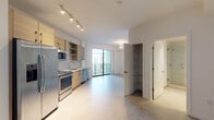 Located on NW 11th Ave in Miami, FL, this modern single-floor unit offers a clean, contemporary design with thoughtful finishes throughout. The open-concept layout seamlessly connects the kitchen and living area, creating a bright and airy atmosphere enhanced by large-format tile flooring that runs continuously through the space.

The kitchen is well-appointed with light wood cabinetry, open display shelving, stainless steel appliances including a side-by-side refrigerator with ice maker, a range, microwave, and dishwasher. A textured tile backsplash and light countertops complete the modern aesthetic. A stacked in-unit washer and dryer provide added convenience.

The living area opens directly onto a private balcony through full-height sliding glass doors, allowing natural light to flood the interior and offering views of the surrounding neighborhood. A ceiling fan adds comfort to this bright room, which also features a built-in shelving nook for storage.

The bathroom is finished to a high standard, featuring large-format porcelain floor tiles, a wood-toned vanity, and a spacious frameless glass-enclosed walk-in shower adorned with elegant marble-look tile from floor to ceiling. The overall ambiance of the unit is clean, contemporary, and move-in ready, reflecting modern Miami urban living.