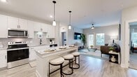 This thoughtfully designed 2-bedroom, 2-bathroom single-story home offers a seamless open-concept layout that connects the kitchen, dining, and living areas into one cohesive, light-filled space. Light wood-style flooring flows throughout the main living areas, complementing the neutral color palette and modern aesthetic.

The kitchen is a standout feature, showcasing crisp white shaker cabinetry, granite countertops, stainless steel appliances, a subway tile backsplash, and a center island with bar seating illuminated by sleek pendant lighting — ideal for both cooking and casual dining.

The living room is bright and welcoming, featuring large windows and a glass-paned door that invite natural light and offer outdoor views. A ceiling fan adds comfort, and the space flows naturally from the kitchen area.

The primary bedroom is generously sized with plush carpet flooring, accompanied by a spacious walk-in closet with wire shelving. The second bedroom also features carpet and ample natural light. Both bathrooms are well-finished, with one featuring a soaking tub and tiled shower surround with wood-look flooring.

Additional highlights include a dedicated laundry room with a full-size washer and dryer, and two closets providing excellent storage throughout this functional and stylish home.