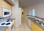 Located at 12325 SW 151st Street in Miami, FL, this single-story unit offers a well-organized layout with a clean, neutral aesthetic throughout. The entryway welcomes you with light tile flooring and immediate access to the main living areas. The spacious living room is bright and airy, featuring large sliding glass doors dressed with vertical blinds that open to the outdoors and allow ample natural light to fill the room.

The kitchen is equipped with wood-toned cabinetry, dark countertops, a coil-top electric range with an over-the-range microwave, a dishwasher, and a sink with an adjacent breakfast bar-style counter. Tile flooring continues throughout the kitchen and hallways, ensuring easy maintenance. A louvered closet provides additional storage nearby.

The bedrooms feature warm wood-style laminate flooring and windows fitted with blinds that allow natural light to filter in. The primary bedroom includes a ceiling fan and a dedicated window overlooking the outdoors, while an additional bedroom offers a similarly bright and clean environment.

The bathroom includes a wide vanity with a single sink, dark countertop, and wood-toned cabinetry, complemented by a tiled walk-in shower with glass doors. A convenient in-unit laundry area with a full-size washer and dryer is also present. The overall design is practical and move-in ready.