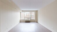 Located at 210 Somerset St W in Ottawa's vibrant Centretown neighbourhood, this studio unit offers a smartly designed, single-floor layout that maximizes every square foot. The open-concept living and dining area is anchored by a large picture window that frames views of the surrounding urban streetscape, flooding the space with natural light. Light-toned laminate flooring runs throughout, contributing to a clean, airy aesthetic complemented by neutral warm-beige walls and white trim.

The kitchen is efficiently laid out with white cabinetry featuring sleek bar-pull hardware, a white coil-top range, and light countertops — all set beneath a drop ceiling with recessed panelling. A short hallway connects the main living area to the remaining rooms, with doors leading to the bathroom and a dedicated closet for storage.

The bathroom is finished with tile flooring, a white vanity with under-sink cabinetry and a mirrored medicine cabinet above, providing practical storage solutions. The entry corridor offers a welcoming transition into the unit, with clean white doors and consistent flooring throughout. Overall, the space presents a functional, well-maintained interior suited to urban living in the heart of Ottawa.