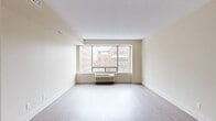 Located at 210 Somerset St W in Ottawa's vibrant Centretown neighbourhood, this studio unit offers a smartly designed, single-floor layout that maximizes every square foot. The open-concept living and dining area is anchored by a large picture window that frames views of the surrounding urban streetscape, flooding the space with natural light. Light-toned laminate flooring runs throughout, contributing to a clean, airy aesthetic complemented by neutral warm-beige walls and white trim.

The kitchen is efficiently laid out with white cabinetry featuring sleek bar-pull hardware, a white coil-top range, and light countertops — all set beneath a drop ceiling with recessed panelling. A short hallway connects the main living area to the remaining rooms, with doors leading to the bathroom and a dedicated closet for storage.

The bathroom is finished with tile flooring, a white vanity with under-sink cabinetry and a mirrored medicine cabinet above, providing practical storage solutions. The entry corridor offers a welcoming transition into the unit, with clean white doors and consistent flooring throughout. Overall, the space presents a functional, well-maintained interior suited to urban living in the heart of Ottawa.