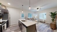 Located in Chippewa Falls, WI, this well-designed 2-bedroom, 2-bathroom single-floor home offers a thoughtful layout with modern finishes throughout. The open-concept kitchen and living area serves as the heart of the home, anchored by a large center island with a built-in sink, white quartz countertops, and dark cabinetry that provides striking contrast. Stainless steel appliances, including a refrigerator, range, and microwave, complement the contemporary aesthetic, while stylish pendant lighting adds warmth overhead. The living room flows seamlessly from the kitchen, featuring durable wood-style flooring, a ceiling fan, and multiple windows that fill the space with natural light. Both bedrooms are carpeted for comfort, each with a ceiling fan or overhead light and windows offering outdoor views. The spacious primary bedroom provides a generous retreat. The two bathrooms are finished with dark wood vanities, white countertops, and wood-style flooring — one features a full soaking tub with shower, and the other a stand-alone shower. A dedicated hallway entry area includes built-in coat hooks, a bench, and a double-door closet, offering practical everyday storage. With four closets total and a clean, neutral color palette throughout, this home balances functionality with modern style.