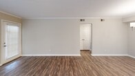 This single-floor residence offers a thoughtfully designed layout with 1 bedroom and 2 full bathrooms. The open living room serves as the heart of the home, showcasing rich dark hardwood-style flooring, crown molding, and a crisp white electric fireplace with a classic mantel shelf as a focal point. Natural light filters in through windows fitted with blinds, while a glass-paneled door provides convenient exterior access directly from the living area.

The kitchen features white shaker-style cabinetry with matte black hardware, a speckled quartz countertop, a classic white subway tile backsplash, and hardwood-style flooring — offering a clean, modern aesthetic with ample storage and prep space.

The bedroom is a comfortable, carpeted retreat equipped with a ceiling fan and its own exterior door, adding both functionality and natural light. It connects directly to a full bathroom that includes a tub/shower combination and access to a well-organized walk-in closet with wire shelving. A second full bathroom further enhances the home's practicality.

Throughout the residence, neutral warm-beige walls provide a versatile backdrop, while consistent flooring choices and clean white trim create a cohesive, move-in-ready aesthetic. The overall ambiance is bright, clean, and efficiently arranged.
