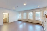 Located at 187 Pearl St in the heart of Burlington, Vermont, this studio unit offers a thoughtfully designed single-floor layout that maximizes every square foot. The open main living area seamlessly integrates sleeping, lounging, and dining functions, with smooth light-colored flooring and clean white walls that create a bright, airy atmosphere. Tall windows allow generous natural light to filter into the space, framed by painted exposed brick that adds a touch of historic character to the otherwise contemporary interior.

The kitchen area is well-appointed with light wood laminate cabinetry, a full suite of white appliances including a range, microwave, dishwasher, and refrigerator, as well as a double-basin sink. Ample upper and lower cabinet storage makes the kitchen both practical and visually cohesive.

The bathroom features a modern vanity with light wood cabinetry, a white countertop, a sleek framed mirror, and a glass-enclosed shower-tub combination, all finished in a clean, neutral palette. A dedicated closet provides additional storage. The unit's efficient design, combined with its updated finishes and prime Pearl Street location in downtown Burlington, makes it a functional and comfortable living space.