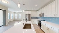 Located in Bonita Springs, Florida, this well-appointed 3-bedroom, 2-bathroom single-story residence offers a thoughtfully designed layout with modern finishes throughout. The open-concept kitchen and living area serves as the heart of the home, featuring crisp white shaker cabinetry, stainless steel appliances including a French door refrigerator and range, a light blue tile backsplash, and a large center island with a white quartz countertop and undermount sink — all illuminated by pendant lighting and recessed fixtures. Light wood-look flooring flows throughout the main living areas, enhancing the bright and airy atmosphere. The primary bedroom is generously sized, filled with natural light from multiple windows, and includes a ceiling fan and access to a walk-in closet with built-in wire shelving. Additional bedrooms feature neutral carpet and ample natural light. The bathrooms are finished with white vanities, quartz countertops, and glass-enclosed walk-in showers. A dedicated laundry room, multiple closets, and two hallways add to the home's functional layout. The unit also includes a private patio, ideal for enjoying Florida's warm outdoor living. The overall design is clean, contemporary, and move-in ready.
