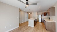 Located at 3506 Bluff Rd in Indianapolis, IN, this 1-bedroom, 1-bathroom unit offers a thoughtfully designed single-level layout with modern finishes throughout. The open-concept living and kitchen area is anchored by a central island featuring a stainless steel sink, sleek white countertops, and pendant lighting overhead. Rich, medium-toned cabinetry lines the kitchen walls, complemented by a full suite of stainless steel appliances including a refrigerator, range, microwave, and dishwasher. Light wood-style flooring flows through the main living areas, enhancing the bright, airy atmosphere created by recessed lighting and a modern ceiling fan. A sliding glass door with vertical blinds allows natural light to fill the living space. The bedroom offers plush carpeting, a ceiling fan, and a generously sized window with blinds, creating a comfortable and restful retreat. A dedicated closet provides convenient storage. The bathroom is cleanly finished with wood-look flooring, a dark-toned vanity with white countertop, and a curved rod tub-shower combination. The overall design presents a clean, contemporary aesthetic well-suited for everyday living.