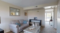 This well-organized single-story unit makes efficient use of its footprint through a thoughtfully designed open-concept layout. The living room features neutral carpet, a ceiling-height soffit detail, and direct sightlines to a sliding glass door that brings in natural light. A dedicated seating area with a large window adds versatility to the living space, which flows seamlessly into the dining area. The dining space features warm hardwood-style flooring, a ceiling fan with light fixture, and a window with blinds that allows ample natural light.

The kitchen is equipped with wood-toned cabinetry, laminate countertops, and white appliances including a range, dishwasher, and built-in microwave. Hardwood-style flooring continues through this area.

The bedroom is a well-proportioned retreat with plush carpet, a ceiling fan, and a sliding glass door opening to a private balcony with outdoor views. A dedicated closet provides storage.

The full bathroom features hardwood-style flooring and a tub/shower combination. A conveniently located in-unit laundry area houses a full-sized washer and dryer, adding practical everyday functionality to the space.
