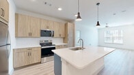 Located at 1910 E State Highway 121 N in Lewisville, TX, this thoughtfully designed one-bedroom residence offers a clean, modern aesthetic across its single floor. Light wood-style luxury vinyl plank flooring runs throughout, tying the space together with a warm, contemporary feel. The open-concept kitchen and living area serves as the heart of the home, anchored by a central island with a white quartz countertop, undermount sink, and pendant lighting above. The kitchen is outfitted with light natural wood cabinetry, a white tile backsplash, and a full suite of stainless steel appliances, including a refrigerator, range, and over-the-range microwave. Recessed lighting and pendant fixtures provide ample illumination throughout the combined space. The bedroom offers a comfortable, well-proportioned layout with a ceiling fan, a large window that invites natural light and outdoor views, and direct access to a dedicated closet featuring double doors for convenient storage. Crisp white walls and clean-lined trim details carry through every room, contributing to a bright, airy ambiance. The overall design reflects a modern, move-in-ready sensibility well-suited for everyday living in the Lewisville area.