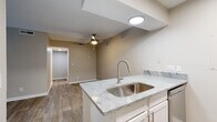 This single-floor residence combines modern updates with functional design throughout its well-organized layout. The open-concept kitchen serves as a central highlight, featuring granite countertops, a peninsula with an undermount stainless steel sink, white shaker-style cabinetry, classic subway tile backsplash, and stainless steel appliances including a refrigerator and electric range. Wood-look luxury vinyl flooring flows seamlessly through the main living areas, lending warmth and continuity to the space.

The living area is bright and inviting, anchored by a ceiling fan and offering access through French doors to an outdoor area, filling the room with natural light and greenery views. The entry foyer offers a clean transition into the open living space, providing a welcoming first impression.

The bedrooms are carpeted for comfort and each includes a ceiling fan with light fixture and windows overlooking lush outdoor scenery, creating a calm, restful atmosphere. The bathroom features a full soaking tub framed by large-format marble-look porcelain tile surround with chrome fixtures, conveying a clean, spa-inspired aesthetic. Wood-look flooring in the bathroom ties it cohesively to the rest of the unit. Neutral warm-beige tones and textured ceilings are consistent throughout, giving the space a cohesive and move-in-ready character.