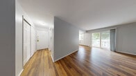Located at 151 Andrew Ave in Naugatuck, CT, this well-appointed one-bedroom, one-bathroom residence offers a thoughtfully designed single-floor layout. Rich hardwood-style flooring runs consistently throughout the unit, lending warmth and visual continuity to every room. The combined living and dining area is generously proportioned, bathed in natural light through large sliding glass doors that open directly onto a private patio, offering pleasant outdoor views of surrounding greenery. Baseboard heating lines the perimeter of the main living spaces, ensuring year-round comfort. The galley-style kitchen is efficiently designed with white cabinetry, granite-look countertops, a speckled tile backsplash, and white appliances including a range and refrigerator, maximizing functionality within the space. The spacious primary bedroom features a wall-unit air conditioner and a large window with outdoor views. Storage is a standout feature, with three closets including a walk-in closet equipped with wire shelving. The bathroom offers a full tub-shower combination with built-in wall niches and clean white fixtures. Gray-toned walls throughout create a calm, neutral palette that complements the warm flooring for a cohesive, move-in-ready aesthetic.
