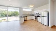 Located at 4359 Sadler Rd in Glen Allen, Virginia, this single-floor unit offers a clean, modern design with a neutral color palette throughout. The open-concept kitchen is well-appointed with white shaker-style cabinetry, a subway tile backsplash, light quartz-style countertops, and a full suite of stainless steel appliances including a refrigerator, electric range, over-the-range microwave, and dishwasher. Light hardwood-style flooring runs through the main living and kitchen areas, creating a bright and cohesive feel. The living area benefits from large sliding glass doors that open to a private balcony, framing views of surrounding greenery and filling the space with natural light. The bedrooms are finished with plush carpeting and feature windows with outdoor views; one bedroom includes a ceiling fan for added comfort. Storage is well-addressed with a spacious walk-in closet outfitted with wire shelving and hanging rods. The unit includes two bathrooms — one with a soaking tub and shower combination, the other with a walk-in shower stall featuring built-in shelving. Both bathrooms are finished with light tile flooring and clean white fixtures, maintaining the consistent modern aesthetic found throughout this thoughtfully designed unit.