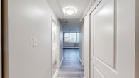 Located at 1320 W Somerville Ave in Philadelphia, PA, this one-bedroom, one-bathroom unit offers a practical and efficiently designed layout across a single floor. The space features light gray luxury vinyl plank flooring throughout, lending a clean, cohesive look to every room.

The combined kitchen and living area serves as the heart of the unit. The kitchen is outfitted with white shaker-style cabinetry, light countertops, a gas range, a refrigerator, and a sink — all arranged for functional use. A corner window placement in the kitchen brings in natural light and offers pleasant outdoor views. The living area is generously proportioned, with a wide bank of windows dressed with vertical blinds that flood the space with natural light and frame views of the surrounding neighborhood.

The bedroom is a well-sized private retreat featuring a closet with sliding doors, a window with a wall-unit air conditioner, and baseboard heating. The neutral white walls and consistent flooring create a calm, adaptable environment.

A hallway connects the main living areas to the bedroom and bathroom, providing a clear and organized flow throughout the unit. The bathroom is cleanly finished with white fixtures and tile wainscoting. Throughout the unit, white panel doors and bright overhead lighting contribute to a crisp, move-in-ready aesthetic.