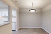 This single-floor unit offers a thoughtfully designed layout that balances open living spaces with functional, well-finished rooms throughout. The living area is anchored by rich, dark hardwood-style flooring and features a set of French doors that allow natural light to filter in while providing access to an outdoor space. A textured ceiling adds a classic touch carried consistently throughout the unit.

The open dining area flows seamlessly from the kitchen and is highlighted by a pendant light fixture overhead. The kitchen is well-equipped with crisp white cabinetry featuring brushed nickel hardware, granite countertops with subtle veining, a deep undermount sink, white appliances, and a clean white subway tile backsplash that lends a bright, polished aesthetic.

The bedrooms are finished with plush carpeting for comfort and include closets for ample storage. One bedroom benefits from windows on two walls, inviting natural light and views of the surrounding exterior, and is equipped with a ceiling fan for added comfort.

The bathroom is finished to a high standard, featuring a wide granite-topped vanity with white cabinetry, a large wall mirror, and a tiled shower-tub combination. Together, the spaces present a cohesive, clean, and move-in ready interior with quality finishes throughout.