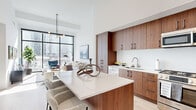 Located at 808 Crawford St in Houston's vibrant downtown, this modern one-bedroom, one-bathroom residence offers a thoughtfully designed open-concept layout with exceptional finishes throughout. Soaring ceilings and floor-to-ceiling windows flood the living area with abundant natural light while framing striking city skyline views. The living room is anchored by a contemporary chandelier and opens seamlessly to the kitchen, which features warm walnut cabinetry extending to the ceiling, a sleek white quartz island with bar seating, stainless steel appliances, and light hardwood flooring that flows throughout the entire residence. The bedroom is generously proportioned, featuring oversized windows with expansive city views, soaring ceilings, and direct access to both the closet and laundry area. The spa-inspired bathroom is a standout feature, offering a long double-vanity with illuminated mirrors, large-format tile flooring, a deep soaking tub with warm stone tile surround, and a frameless glass walk-in shower. A dedicated laundry area with stacked units adds everyday convenience. Clean white walls, high ceilings, and modern finishes throughout create a bright, airy, and sophisticated urban living experience.