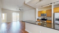 This multi-level home spans four floors, offering a well-organized layout with 2 bedrooms, 4 bathrooms, a garage, and thoughtfully distributed living spaces. The ground level houses the attached garage, featuring a concrete floor, angled ceiling, and overhead storage rail — a practical and functional space for vehicles or additional storage.

The main living floor presents an open-concept kitchen and living room combination. The kitchen is outfitted with warm honey-toned wood cabinetry, dark granite countertops, stainless steel appliances including a range, microwave, refrigerator, and dishwasher, complemented by classic tile flooring and a tile backsplash. The adjoining living area features rich hardwood flooring, a ceiling fan, track lighting, and sliding glass doors that invite natural light.

Carpeted staircases with white railings and handrails connect each level, providing a clean and consistent transition throughout the home. The upper bedroom floors include a generously sized primary bedroom with plush carpet and a ceiling fan, along with a dedicated closet equipped with built-in shelving and a narrow vertical window with outdoor views. The bathrooms are finished with tile flooring and clean, neutral fixtures.

The uppermost floor offers a compact but functional footprint, completing this vertical home's efficient and cohesive design.
