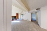 Located at 1410 Lake Blvd in Davis, CA, this two-story home offers four bedrooms and two bathrooms across a thoughtfully laid-out floor plan. The main level serves as the heart of the home, featuring a spacious living room with dramatic vaulted ceilings that lend an open, airy feel. A wood-framed fireplace with a tiled hearth and an adjacent built-in wood bookshelf serve as the room's focal point, while carpet flooring and natural light from a nearby window create a warm, inviting atmosphere. A staircase rises from the living area, connecting the main level to the upper floor. The kitchen is efficiently designed with warm wood cabinetry, ample counter space, a stainless steel range, and a double sink — providing all the essentials for daily use. The bedrooms are carpeted and bright, with clean white walls; the primary bedroom offers generous proportions, while additional bedrooms include features such as ceiling fans. The upper floor houses additional bedrooms, making the layout practical for households needing dedicated private spaces. The two bathrooms are functional and well-appointed, featuring tub-shower combinations, vanities, and tile flooring. Overall, this home provides a comfortable and functional living environment in a convenient Davis location.