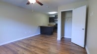 This single-floor space offers a clean, open-concept layout that seamlessly connects the living area and kitchen, creating a bright and functional environment. Rich hardwood flooring extends throughout the main living space, adding warmth and a timeless aesthetic to the interior.

The kitchen is thoughtfully designed with dark cabinetry, granite countertops, and a full suite of stainless steel appliances, including a range and microwave. A kitchen island provides additional counter space and doubles as a casual dining or prep area, making it a central hub of the home.

A ceiling fan in the living area ensures year-round comfort, complementing the practical and well-appointed design of the space. Adjacent to the main living area, a walk-in closet offers generous storage, adding to the overall functionality of the layout.

The neutral, light-toned walls throughout create a versatile backdrop, allowing the space to feel open and airy. The combination of modern finishes, durable flooring, and smart use of space makes this unit a well-rounded and move-in-ready environment suited for everyday living.