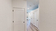 This well-appointed single-floor unit offers a thoughtfully designed layout that maximizes functionality within a compact footprint. The open-concept kitchen serves as a central highlight, featuring crisp white shaker cabinetry, a herringbone tile backsplash, stainless steel appliances including a refrigerator, electric range, microwave, and dishwasher, as well as light wood-toned luxury vinyl plank flooring that flows throughout the main living areas. A sliding glass door connects the living space to a private balcony, allowing natural light to fill the interior and offering views of the surrounding area.

The bedroom is finished with plush carpeting for added comfort and includes a closet with double doors and matte black hardware — a design detail echoed throughout the unit via consistent black accents on doors and fixtures. A sliding door connects the bedroom directly to the main living area, further enhancing the sense of openness and connectivity within the space.

The full bathroom is clean and modern, featuring a tiled tub-shower combination with full-height wall tile, matte black fixtures, a toilet, and a vanity with countertop storage. A hallway connects the key areas of the unit, lined with panel doors and recessed lighting overhead. The overall aesthetic is fresh and contemporary, with a neutral white palette, clean lines, and modern hardware throughout.