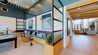 Located at 9840 Carroll Canyon Road in San Diego's Scripps Ranch neighborhood, this single-story amenity space is designed with a contemporary aesthetic that blends functionality with sophisticated style. A cohesive palette of teal, warm wood tones, and crisp white carries throughout the interior, creating a polished and inviting atmosphere.

The main lounge area anchors the space with soaring ceilings, floor-to-ceiling windows, and an expansive seating arrangement featuring leather and upholstered sofas, accent chairs, and a large wall-mounted display. Abundant natural light floods the room, offering views of the surrounding exterior grounds.

The fully equipped community kitchen showcases teal cabinetry, stainless steel appliances including a double wall oven and full-size refrigerator, a white quartz island with bar seating, and exposed wood beam ceilings that add warmth overhead.

Semi-private booth seating areas, framed by glass and metal partitions with teal accent walls and curated artwork, provide intimate spaces for focused work or casual gatherings. Additional lounge nooks offer built-in bench seating with decorative pillows.

The game room features dramatic globe pendant lighting, floor-to-ceiling glazing with outdoor palm tree views, and game tables including billiards, creating a lively yet refined recreational environment.