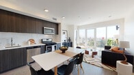 Located at 5750 Hollywood Blvd in Los Angeles, this contemporary residence offers a thoughtfully designed open-concept layout that seamlessly connects the kitchen, dining, and living areas. The kitchen is outfitted with dark wood cabinetry, a marble-inspired tile backsplash, white quartz countertops, and a full suite of stainless steel appliances, including a gas range, dishwasher, and built-in microwave. A dining area sits adjacent to the kitchen, providing a comfortable space for everyday meals. The living room is bathed in natural light, with large sliding glass doors that open to a private balcony offering expansive views of the Los Angeles skyline and surrounding neighborhoods. The two bedrooms each feature floor-to-ceiling sliding glass doors that frame picturesque city and rooftop views, creating bright, airy retreats. The bathrooms are clean and modern, featuring white subway tile surrounds, soaking tub-shower combinations with built-in niches, and wood-look flooring that carries throughout the unit. The overall aesthetic is contemporary and cohesive, combining warm wood tones with crisp white walls for a balanced, urban living experience.