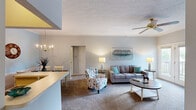 Located at 101 Post Oak Path in Georgetown, Kentucky, this single-floor residence offers a well-organized layout with two bedrooms and two full bathrooms. The open-concept living and dining area forms the heart of the home, where soft neutral tones and carpet flooring create a warm, inviting atmosphere. The living room features crown molding, a ceiling fan, and generous wall space, while the adjacent dining area is distinguished by an elegant chandelier, chair rail molding, and a soft blue accent wall. The galley-style kitchen is lined with warm oak cabinetry on both sides, offering abundant storage and counter space, complete with a double sink and white appliances including a range and dishwasher. A pass-through connects the kitchen directly to the dining area, enhancing the flow of the space. The spacious primary bedroom provides a comfortable retreat with carpeted flooring, a textured ceiling, and access to a closet. The second bedroom is equally well-proportioned and features its own closet. Both bathrooms are finished with tile flooring and shower-tub combinations, one featuring warm wood vanity cabinetry. A hallway and closet round out the practical layout, making this a functional and comfortable home.