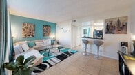 Located at 2000 Gandy Blvd N in Saint Petersburg, FL, this well-appointed one-bedroom, one-bathroom unit offers a thoughtfully designed layout across a single floor. A cohesive teal and neutral color palette runs throughout the space, lending it a lively yet comfortable ambiance.

The living room features large windows dressed with teal curtains that allow natural light to fill the room. Tile flooring extends across the main living areas, providing a clean and durable surface. A bar-height counter separates the living area from the kitchen, complete with modern bar stools — ideal for casual dining or entertaining.

The kitchen is outfitted with white cabinetry, dark granite-style countertops, a mosaic tile backsplash, a gas range, and a double-basin sink, offering a functional and stylish space for cooking.

The bedroom continues the teal accent theme with a bold feature wall, a well-sized window with natural light, and a dedicated closet. The space comfortably accommodates a full-sized bed with room to spare.

The bathroom includes a tub-shower combination, white vanity cabinetry with dark countertops, a large mirror, and tile flooring, maintaining the clean aesthetic found throughout the unit. Overall, this space delivers a cohesive, vibrant design with practical features throughout.