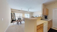 Located at 705 Bridgeport Ave in Streetsboro, Ohio, this single-floor residence offers a well-designed open-concept layout that seamlessly connects the kitchen, dining, and living areas. The kitchen features warm oak cabinetry, light countertops, and a peninsula with a breakfast bar that overlooks the combined dining and living space. Large windows throughout the main living area flood the space with natural light, and a sliding glass door in the living room opens to an outdoor view, enhancing the sense of openness. Ceiling fans are present in the main living area for added comfort.

The primary bedroom is generously sized with plush carpeting, a broad window for natural light, and vaulted ceiling accents. It includes a walk-in closet with built-in shelving and an en-suite bathroom equipped with a walk-in shower, oak vanity cabinetry, and tile flooring. The second bedroom is equally comfortable, also featuring carpet flooring, a window, and ample closet space. A second full bathroom serves this room, complete with a shower-tub combination and tile flooring. An additional bathroom area includes dual oak vanities flanking a set of louvered bi-fold doors, offering generous storage. The overall ambiance is warm, neutral, and inviting throughout.