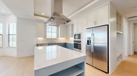 Located in Scottsdale, AZ, this single-story 2-bedroom, 2-bathroom home offers a thoughtfully designed layout with quality finishes throughout. The open kitchen is a true centerpiece, showcasing striking two-tone cabinetry with crisp white uppers and bold blue lowers, gleaming quartz countertops, stainless steel appliances including a built-in wall oven, microwave, and French door refrigerator, plus a large island with integrated shelving and a statement stainless steel range hood. A built-in desk area with matching blue cabinetry adds practical workspace. Light hardwood flooring runs through the main living areas, while plush carpet adds warmth to the bedrooms. The spacious primary bedroom features a bay window arrangement that floods the room with natural light and offers views of the surrounding Scottsdale landscape. The second bedroom is equally well-lit with its own ceiling fan. Both bathrooms are finished with clean tile work, including a full tub-shower combination with classic subway tile surround. A dedicated laundry room houses a full-size washer and dryer on tile flooring. A built-in mudroom-style storage nook with cubbies and hooks adds everyday functionality. Each bedroom includes a walk-in closet, completing this well-organized and modern Scottsdale home.